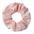 Détail d'un chouchou en satin rose avec motif de pêches et feuilles sur fond blanc pur - Pomme Rose