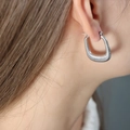 Orecchini a cerchio rettangolari a spirale in acciaio color argento indossati da modella - F1104 Forma U Filettato / Color Acciaio
