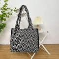 Knitted tote bag with black and white wave pattern hanging on a white folding chair - Wave Black