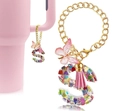 Close-up of letter S resin keychain with colorful sequins and pink tassel on a cup handle - Letter S