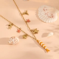 Macro detail of ocean themed gold necklace with fish shell and starfish charms - Orange Clownfish Style (1105 Necklace)