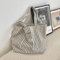 Detailed view of the striped canvas tote bag featuring an outer pocket and woven brand label - Navy Blue Stripes
