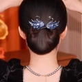 Détail d'une pince à cheveux élégante cygne noir avec cristaux brillants sur un chignon - Cygne Bleu