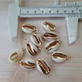 Makro-Detail von natürlichen Kauri-Muschelanhängern mit vergoldeten Kanten für DIY-Schmuck - Elfenbeinweißgold geränderte Muschelscheibe
