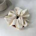 Close-up of premium satin scrunchie in cream on a wooden display stand for hair styling - Off White