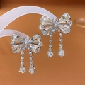 Macro detail of silver bow earrings with sparkling crystals and elegant fringe drops - Bow Tassel Earrings (925 Silver Pin) / Silver