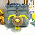 Cute fuzzy brown plush keychain with yellow legs hanging on a blue denim tote bag - Khaki