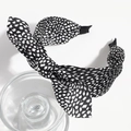 Detail view of fabric headband featuring a large black and white polka dot bow design - Small Leopard Black