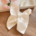 Macro shot of white satin silk scarf folded into star shape on wooden surface - Cream