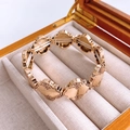 Detailed close-up of gold clover charms with vintage embossed edges on elastic bracelet - Gold