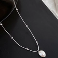 Détail du collier à perles argentées avec pendentif perle baroque sur fond noir - Argenté
