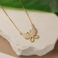Gold-plated butterfly necklace with sparkling zircon on a white stone background - Butterfly / Gold