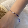 Macro detail of handmade woven bead bracelet with pearl and blue cord on wrist - Royal Blue