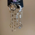 Detalle de pendientes vintage de sol dorado y luna de perlas con borlas de estrellas - Dorado