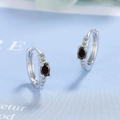 Macro shot of silver huggie earrings with oval black zircon and clear stone accents - Black Zirconia