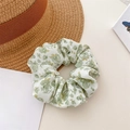 Floral print green fabric scrunchie with white and yellow accents on straw background - Rose Green