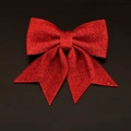 Detailansicht einer roten Glitzer-Weihnachtsschleife auf einem schwarzen Holzhintergrund - Größe 5 - 1 Stück [21*17cm] / Rot