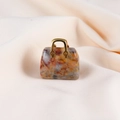 Macro shot of polished orange and grey natural stone handbag pendant with gold clasp - Crazy Agate