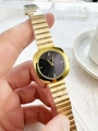 Detail of square gold watch with black dial and metal chain strap in a lifestyle setting - Gold Band Black Dial