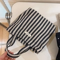 Detail of striped canvas tote bag with a woven simple wish label and dual handles - Striped