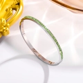 Detail of silver bangle featuring channel-set green square crystals on smooth silk fabric - Silver + Green Zirconia