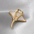 Macro shot of gold manta ray pendant with white shell inlay on a grey silk fabric - White Stingray