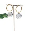 Macro view of 25mm gold stainless steel hoop earrings with grey natural shell pendants - 25mm
