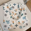 Detailed view of cream-colored floral canvas tote bag with blue rose and orange daisy prints - T-21 White Background with Blue Leaves and Blue Pink Small Flowers