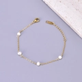 Vista macro di un bracciale dorato in acciaio con perla d'acqua dolce e marchio K18 - Bracciale / Oro 18K