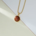 Dettaglio macro della collana a sfere dorate con pendente rotondo in pietra dorata - Pietra del Sole Marrone