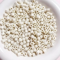 Macro shot of 6mm white cylindrical acrylic beads with holes in a ceramic bowl - Creamy White