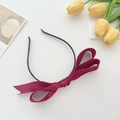 Detail of elegant wine red satin bow headband on white background with tulips - Burgundy