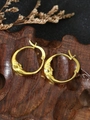 Macro shot of gold moon face earrings with crystal eyes on a rustic wood background - Gold