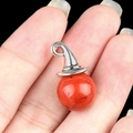 Silver wizard hat pendant with round red agate stone held on a finger for scale - Red Jasper