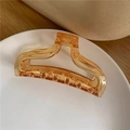 Close-up of amber acrylic hair claw clip on white tray showing glossy resin texture - Light Yellow