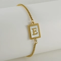 Close-up of gold box chain bracelet with mother of pearl shell initial E square charm - Letter E