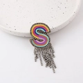 Macro detail of letter S brooch with colorful embroidery and sparkling rhinestone tassels - S