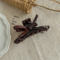 Close-up of elegant burgundy acetate bow hair claw clip on a rustic fabric background - Dark Brown