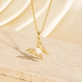 Gold butterfly necklace with white floral accent and crystals on a stone background - BXL0256-14 Gold Flower Butterfly