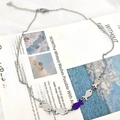 Silver necklace with five fish pendants featuring one purple fish on vintage paper - Purple Fish Upstream Necklace