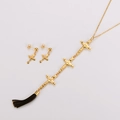 Dettaglio di parure in acciaio inossidabile dorato con croci e nappa nera elegante - Oro