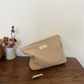 Detail of warm apricot corduroy cosmetic bag with simple wish label on wooden table - Khaki