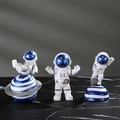 Tre figurine di astronauti in resina bianca e blu in varie pose su marmo nero lucido - Un Set Blu Interstellare