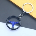 Close-up of a racing steering wheel keychain in black and blue zinc alloy on a wooden desk - Blue Steering Wheel