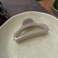 Close-up of a 10cm marbled light brown hair claw clip on a decorative beige tray - Light Nude Pink
