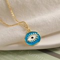 Close-up of golden necklace with blue and white enamel evil eye pendant on white fabric - Blue (Irregular)