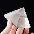 Hand die een heldere natuurlijke kwartskristallen piramide vasthoudt - 6cm