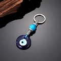 Detail of blue glass evil eye keychain with blue beads and metallic ethnic ornaments - Round Blue Glass Eye