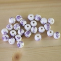Macro detail of white ceramic beads with purple floral patterns on a wooden surface - No.37-Purple Floral