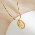 Macro detail of gold plated necklace with H letter pendant and crystal oval frame - Letter H